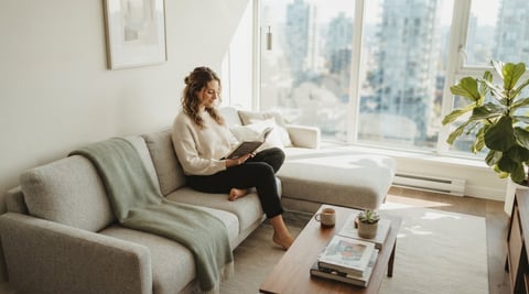 A relaxed young professional reading in a bright modern condo
