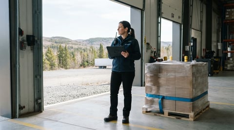 Warehouse supervisor checking shipping status on a tablet at a loading dock